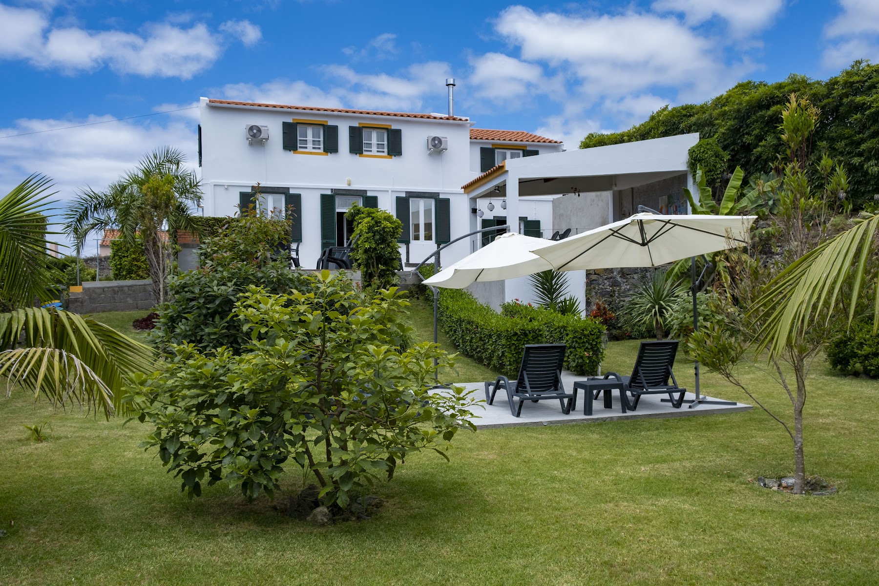 Casa da Quinta white exterior with garden seating and umbrella